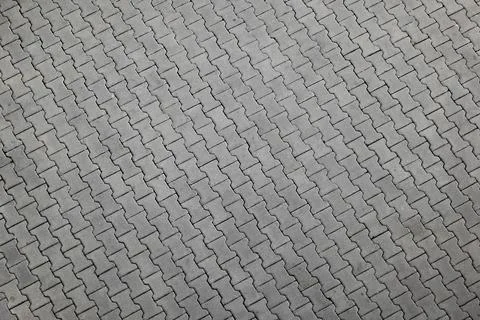 Gray interlocking pavement bricks forming a textured pattern suitable for Stock Photos