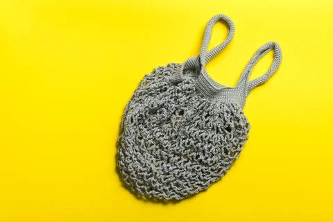 Gray knitted bag string bag lies on a yellow background. Stock Photos