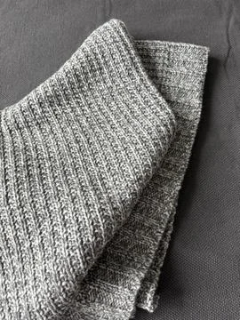 Gray knitted fabric with textured pattern folded on gray textile background Photos