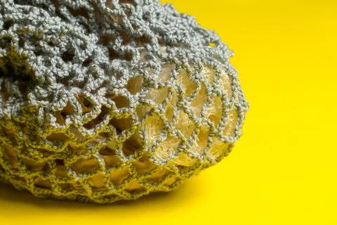 Gray knitted string bag with loofah lies on a yellow background. Stock-Fotos
