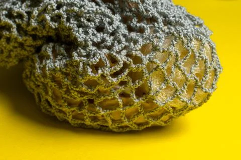 Gray knitted string bag with loofah lies on a yellow background. Stock Photos