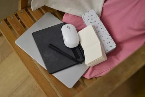 Gray laptop black graphics tablet mouse notebooks on pink fabric wooden chair Foto stock