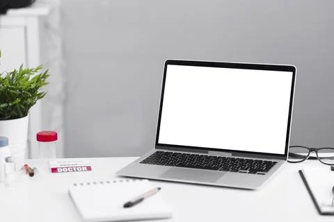 Gray laptop on a white table in a doctor's office. Stock Photos