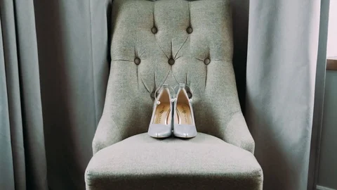 A gray large armchair is standing by the window. On the armchair are women's sho Stock Footage 120681830