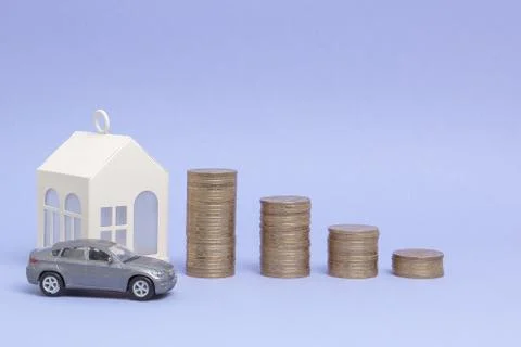 Gray machine model and home with coins in the form of a histogram on a purple Stock Photos