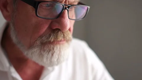 A gray mature man with glasses while working with a laptop. Happy old age Stock Footage 120923011