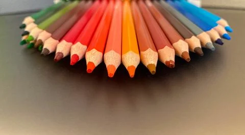 On a gray metal background, there are multi-colored pencils for drawing. Stock Photos