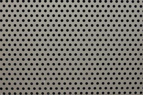 Gray metal panel shows a pattern of black circular perforations Stock Photos