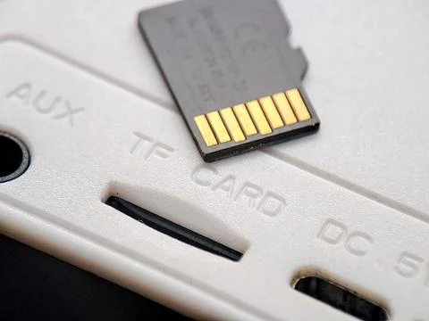 Gray micro SD card resting on a white plastic surface near its slot, symbol.. Stock Photos