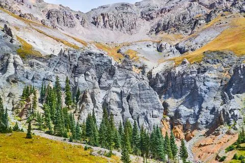 Gray mountain range with columns of rock and pine trees at base Fotos Stock