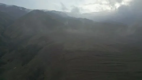 Gray mountains in cloudy weather, clouds flying on the ground, snowy cliff tops. Video stock 253769735