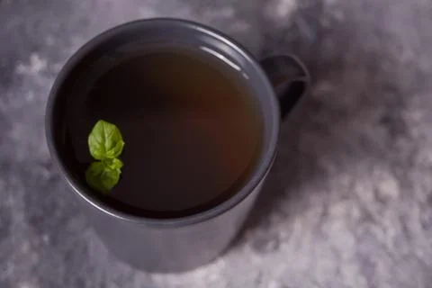 Gray mug of mint tea on dark stone background. Top view. Stock Photos