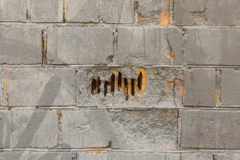 Gray painted brick wall with a broken block Foto stock