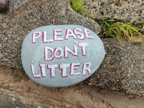 Gray painted kindness stone reading Please Don't Litter Stock Photos