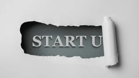 Gray paper is torn over blue background with word "start up", stop motion. Vídeos de archivo 121359648