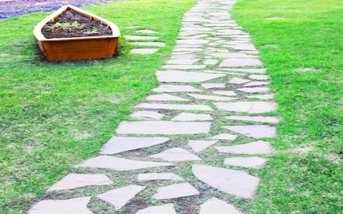Gray paving slabs, paved path, among greenery in a shady park. Shallow depth of Stock Photos