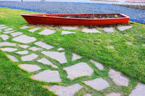 Gray paving slabs, paved path, among greenery in a shady park. Shallow depth of Stock Photos