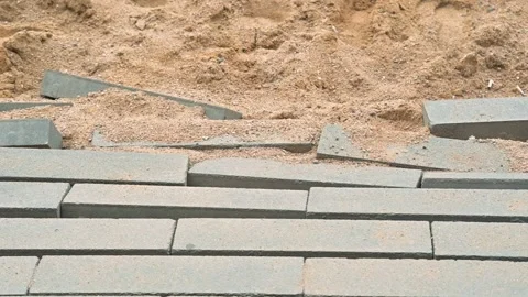 Gray paving stones on a sandy surface to create a pathway. The action involves Vídeo Stock 344675409