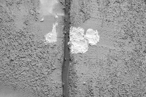 Gray plastered wall with white putty spots showing repair work and wall patching Stock Photos
