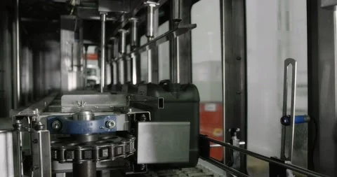 Gray plastic bottles move along a conveyor line to fill and pack motor oil. Stock Footage 166282967