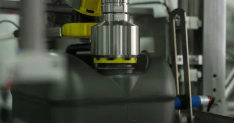 Gray plastic bottles move along a conveyor line to fill and pack motor oil. Stock Footage 166285064