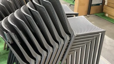 Gray plastic outdoor chairs stacked in a retail store display offering Stock Footage 345178290