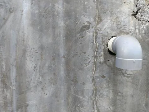 Gray plastic pipe protrudes from a weathered concrete wall in thailand. Perfect  Stock Photos