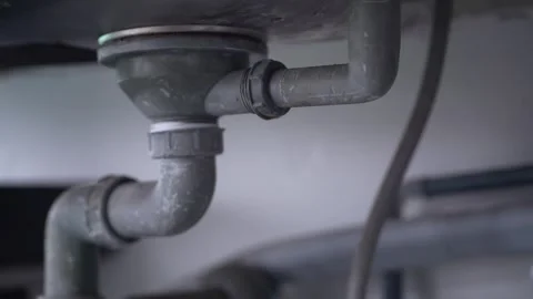 Gray plastic PVC drain pipe system installed beneath a kitchen sink basin Video stock 344704639
