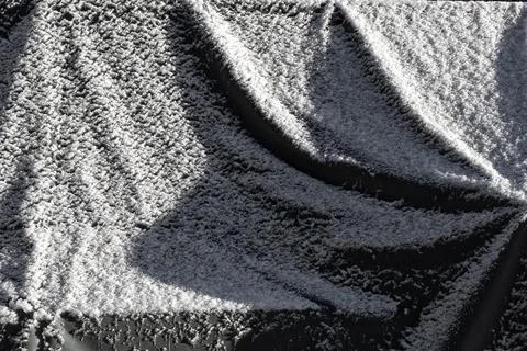 A gray plastic tarp surface covered with a layer of snow, creating a cold win Stock Photos