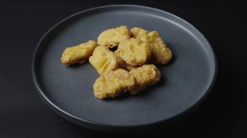 A gray plate is rotating in the frame, chicken nuggets are on the plate.  Stock Footage 304535083