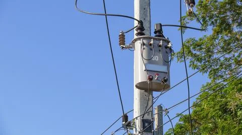 Gray power transformer installed on concrete pole Stock Photos