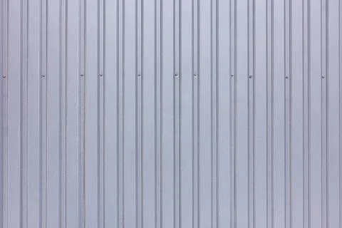 Gray profiled fence made of galvanized corrugated board with vertical rails. Stock Photos