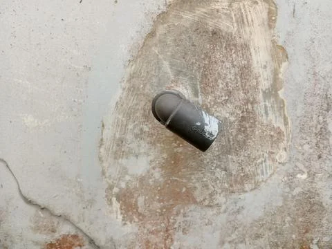 Gray PVC pipe elbow on weathered concrete wall Stock Photos