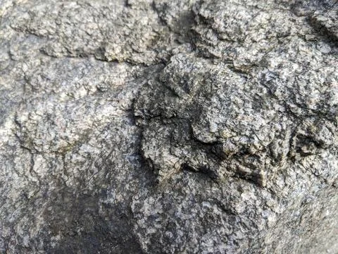Gray rock surface texture with natural cracks in close up outdoor daylight Stock Photos