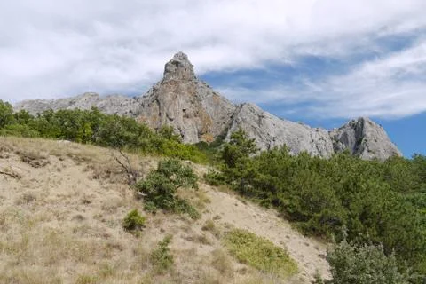 The gray rock is triangular in shape against the blue sky with white divorces 스톡 사진
