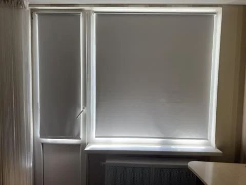 Gray roller blinds with a full blackout effect on the window and balcony  Stock Photos