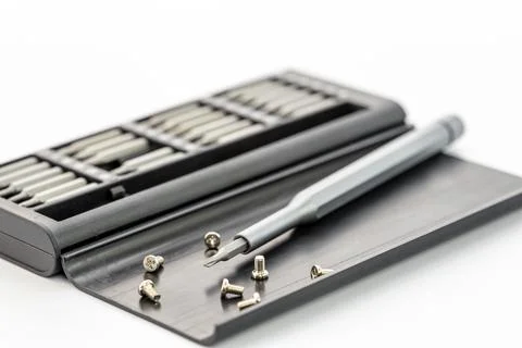 Gray screwdriver and various screws are positioned on a black case Stock Photos