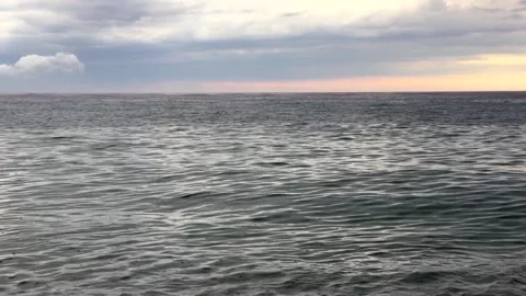 Gray sea at sunset under rain clouds. Gentle waves, distant rainfall and Видео 337777150