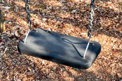 The gray seat of an empty swing. Stock Photos