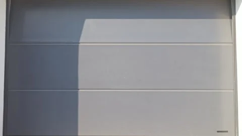 Gray sectional garage door is opening with household items visible inside Stock Footage 334256778