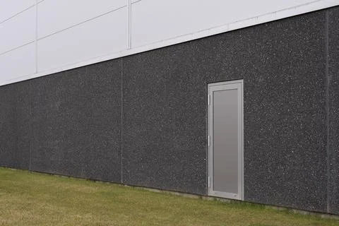 A gray security door without a handle on a dark gray concrete storage buildin Stock Photos