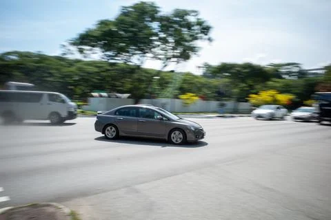 Gray sedan moves smoothly down city road Stock Photos