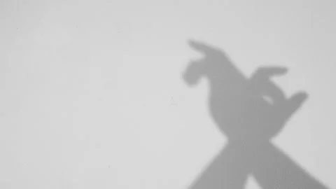 Gray shadow of hand doing bird pose against pink wall Stock Footage 251413801