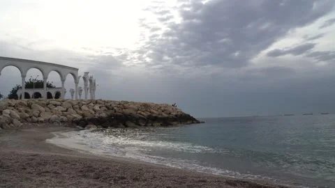 Gray sky and clouds. The gently wavy coast and the ancient columns behind it Stock Footage 240651667