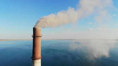 Gray smoke comes out of large brick chimney in the factory against a clear blue Stock Footage 118346195