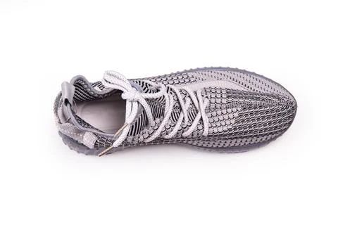 Gray sneaker close-up featuring textured knit upper, light gray laces, transl Stock Photos