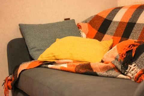 A gray sofa and an orange checkered plaid with blue and yellow pillows at home Stock Photos