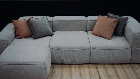 Gray sofa with brown and dark gray cushions, dark background. 4k video Stock Footage 232055679