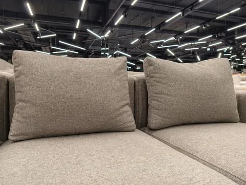 A gray sofa with large throw pillows, available for sale in a furniture store Stock-Fotos