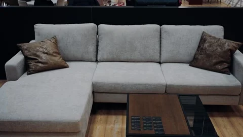 Gray sofa with two brown leather pillows in the office, next to a small black Stock Footage 231507559